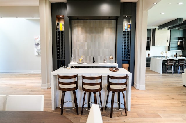 dining space with indoor wet bar, baseboards, and light wood-style floors