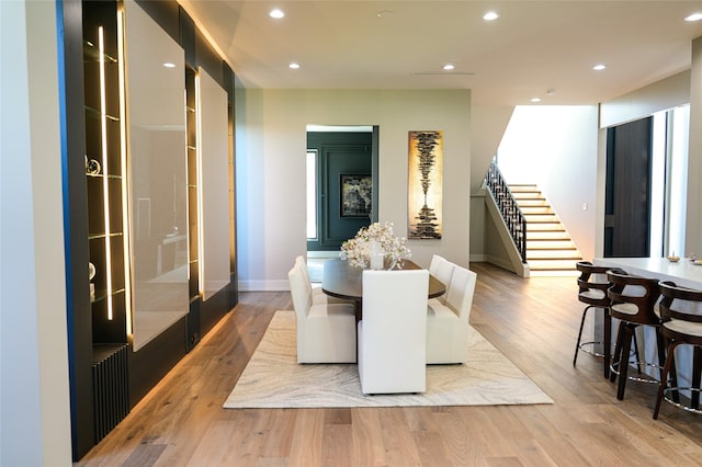 dining space featuring light wood finished floors, stairway, recessed lighting, and baseboards