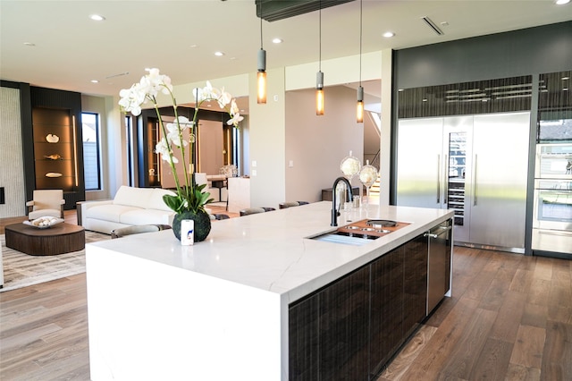 kitchen featuring wood finished floors, modern cabinets, open floor plan, and a sink