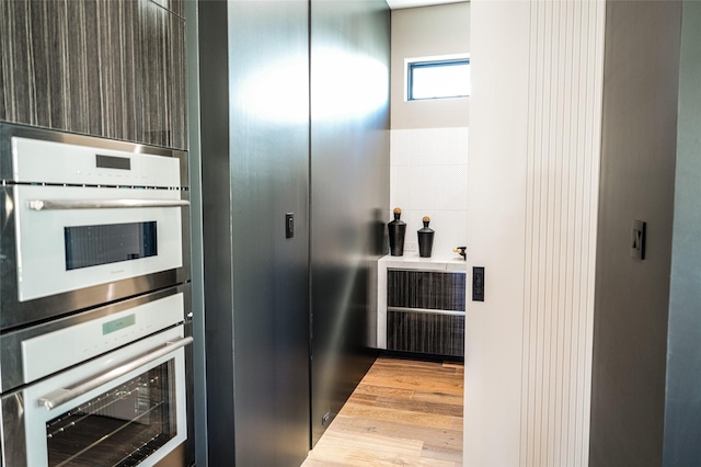 kitchen with dark brown cabinetry, double oven, modern cabinets, and wood finished floors