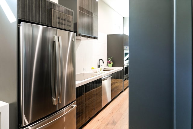 kitchen featuring a sink, light countertops, light wood-style floors, appliances with stainless steel finishes, and modern cabinets