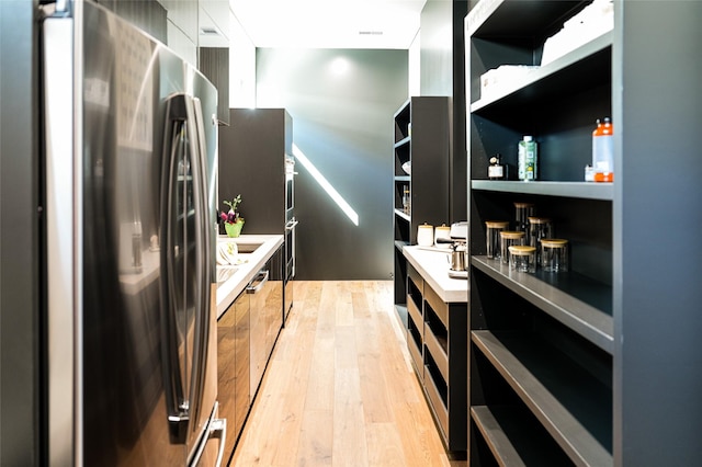 kitchen featuring open shelves, light wood finished floors, light countertops, and freestanding refrigerator