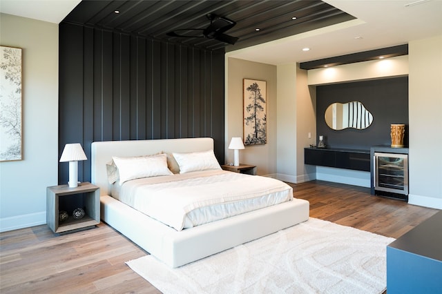 bedroom with baseboards, wood finished floors, and beverage cooler