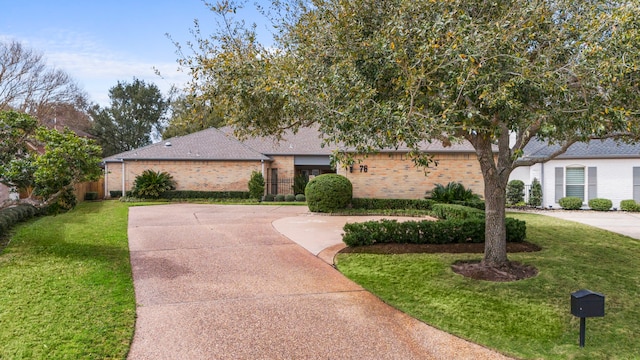 view of front facade featuring brick siding, driveway, and a front lawn