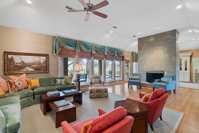 living room with visible vents, a tiled fireplace, lofted ceiling, wood finished floors, and recessed lighting