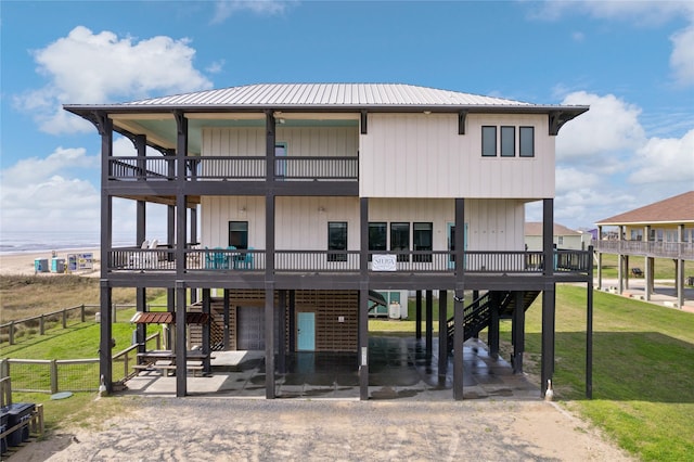 view of front of house with metal roof, stairs, fence, a patio area, and a front lawn