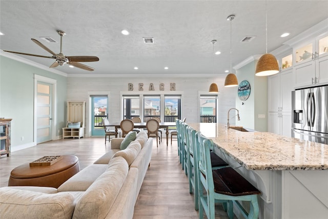 kitchen with open floor plan, a sink, visible vents, and crown molding