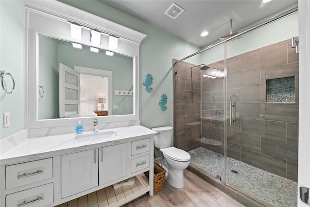 bathroom featuring a stall shower, visible vents, toilet, wood finished floors, and vanity