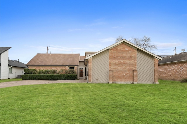 view of front facade featuring driveway, brick siding, and a front lawn