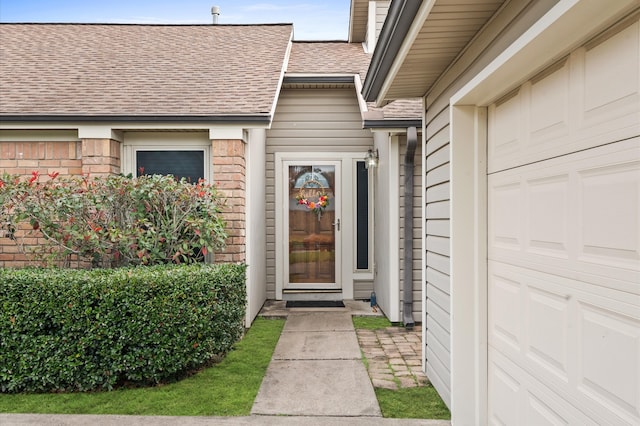 view of exterior entry featuring brick siding and roof with shingles