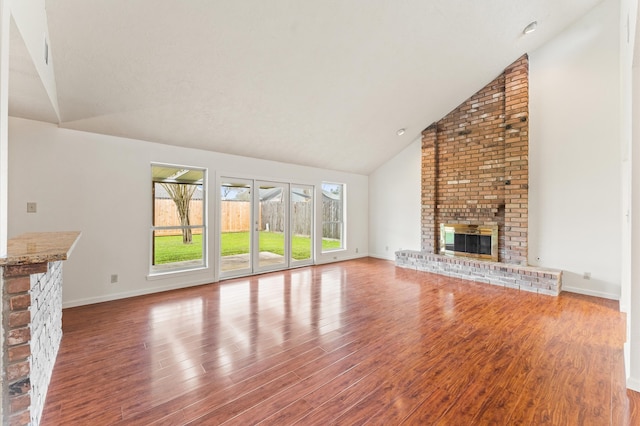 unfurnished living room with high vaulted ceiling, a fireplace, wood finished floors, and baseboards