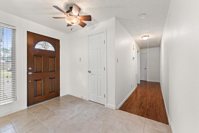 foyer entrance featuring a ceiling fan, a textured ceiling, baseboards, and light tile patterned floors