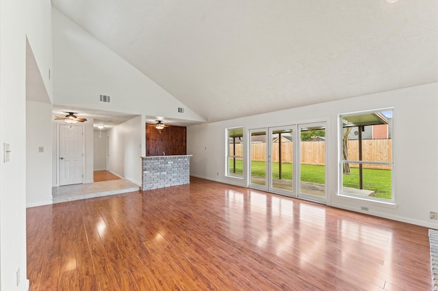 unfurnished living room featuring baseboards, visible vents, a ceiling fan, wood finished floors, and high vaulted ceiling