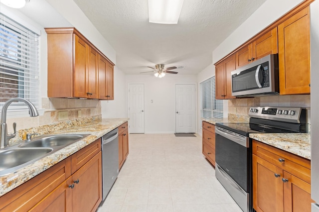 kitchen featuring stainless steel appliances, brown cabinetry, a sink, and backsplash