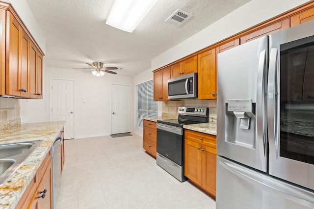 kitchen featuring tasteful backsplash, appliances with stainless steel finishes, visible vents, and brown cabinets