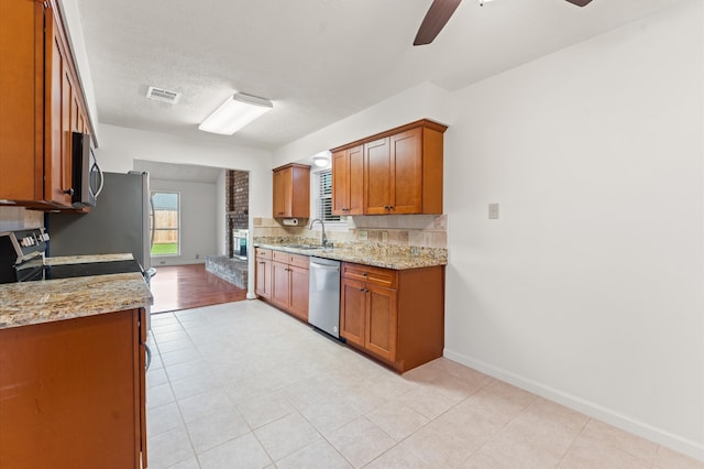 kitchen with a sink, visible vents, appliances with stainless steel finishes, decorative backsplash, and brown cabinetry