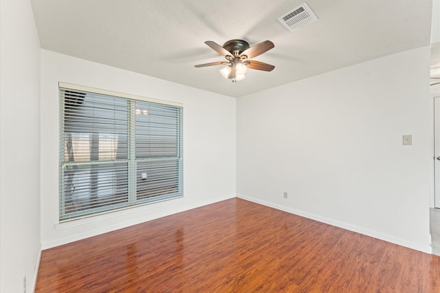 unfurnished room featuring baseboards, visible vents, a ceiling fan, wood finished floors, and a textured ceiling