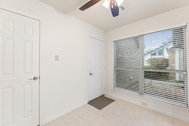 entryway with a ceiling fan, light tile patterned flooring, visible vents, and baseboards