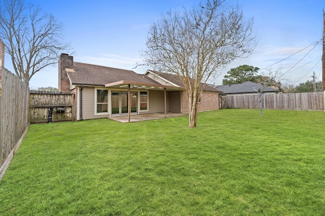 back of property featuring brick siding, a chimney, a lawn, a patio area, and a fenced backyard