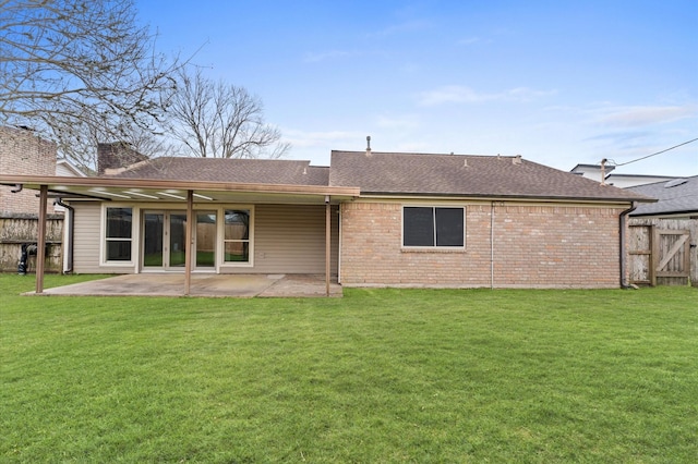 back of house featuring brick siding, a lawn, a patio area, and fence