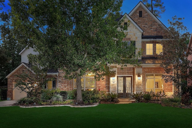 traditional home with an attached garage, french doors, a front yard, and brick siding