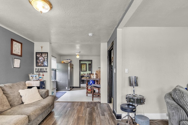 living area with a textured ceiling, wood finished floors, and baseboards