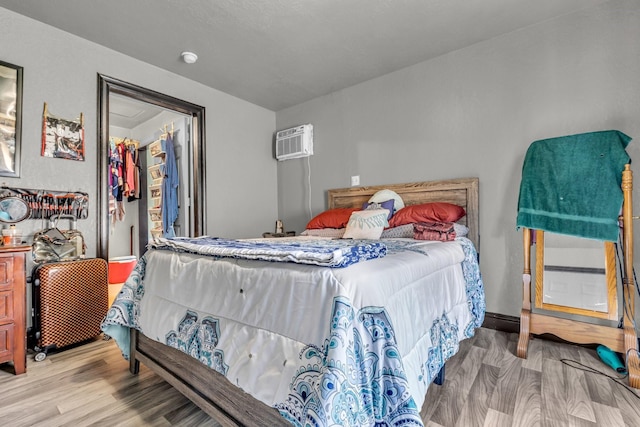 bedroom with an AC wall unit and wood finished floors