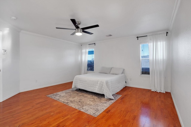 bedroom featuring ornamental molding, wood finished floors, visible vents, and baseboards