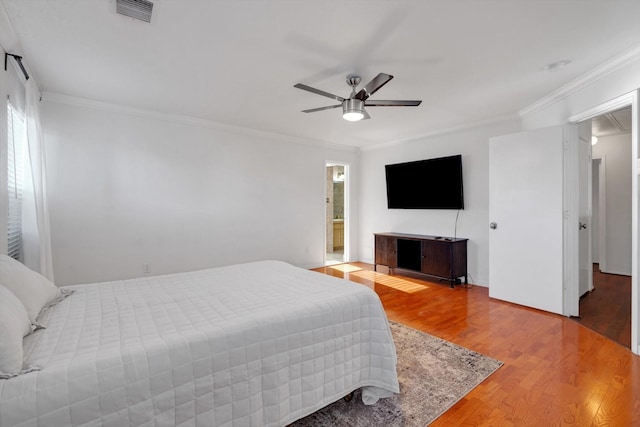 bedroom featuring ceiling fan, wood finished floors, visible vents, ornamental molding, and attic access