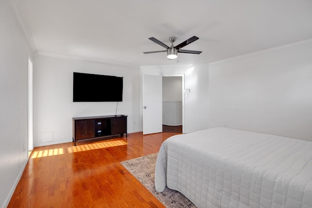 bedroom featuring baseboards, wood finished floors, a ceiling fan, and crown molding