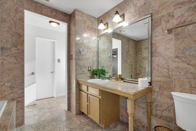 bathroom with marble finish floor, tile walls, toilet, and vanity