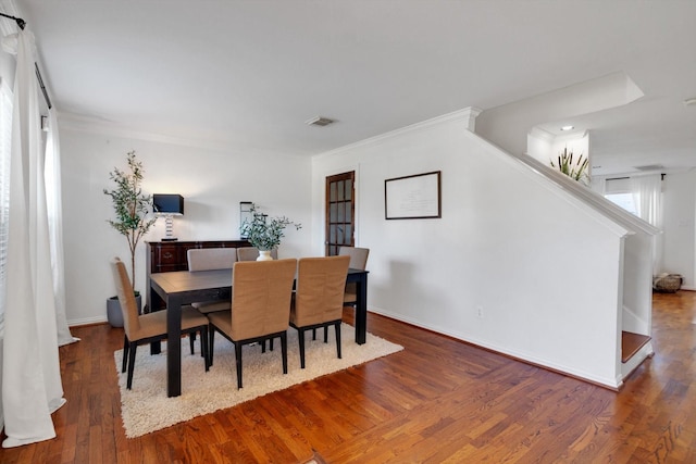 dining space featuring baseboards, visible vents, stairway, wood finished floors, and crown molding