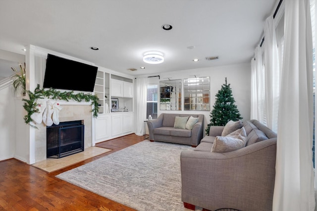 living room with visible vents, a premium fireplace, ornamental molding, wood finished floors, and recessed lighting