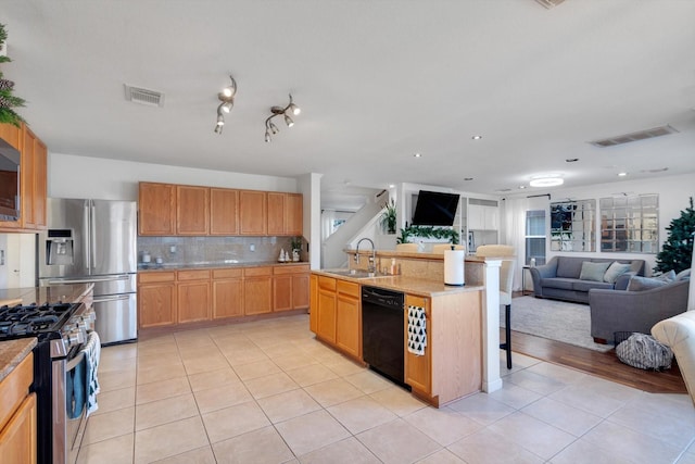 kitchen featuring tasteful backsplash, visible vents, open floor plan, stainless steel appliances, and a sink