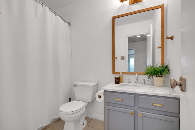 full bathroom featuring toilet, baseboards, and vanity