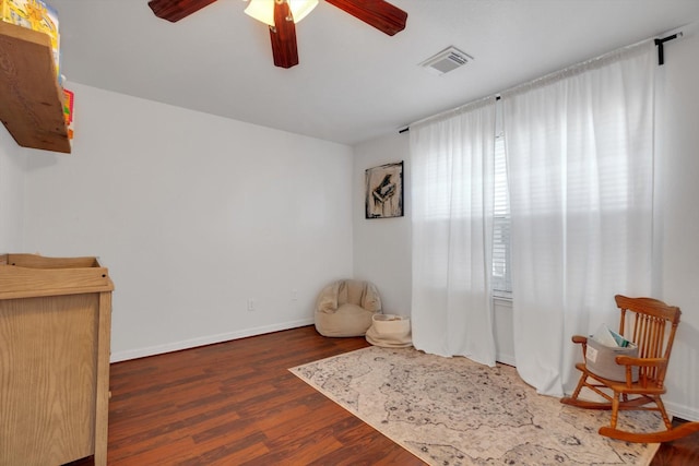 living area featuring a ceiling fan, wood finished floors, visible vents, and baseboards