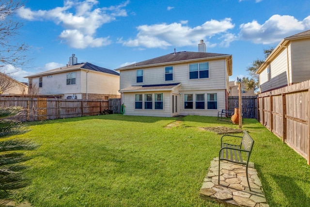 back of property with a yard, a chimney, and a fenced backyard