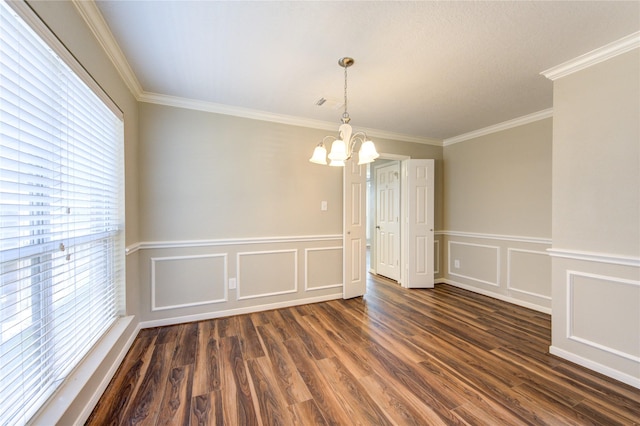 spare room with a chandelier, a decorative wall, dark wood-style flooring, and ornamental molding