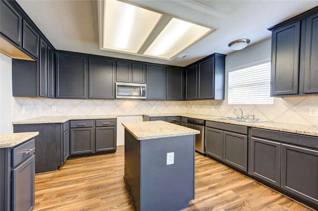 kitchen featuring appliances with stainless steel finishes, a sink, light wood-style flooring, and light stone countertops