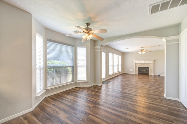 unfurnished living room featuring dark wood-type flooring, a fireplace, visible vents, and a ceiling fan