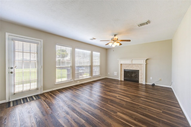 unfurnished living room featuring dark wood-style flooring, visible vents, a fireplace, and a textured ceiling