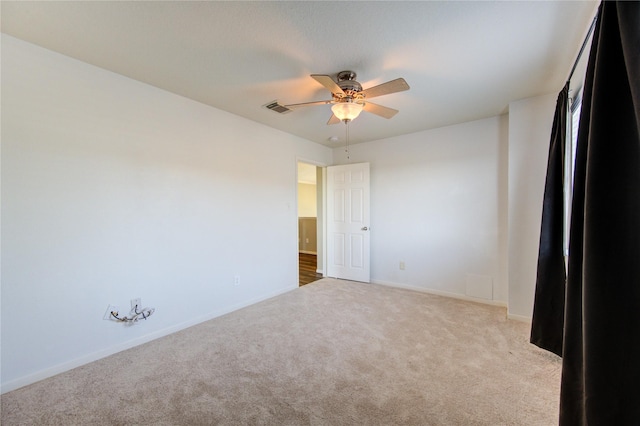 carpeted empty room featuring baseboards, visible vents, and a ceiling fan