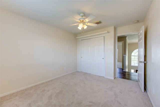 unfurnished bedroom with light carpet, baseboards, visible vents, ceiling fan, and a closet