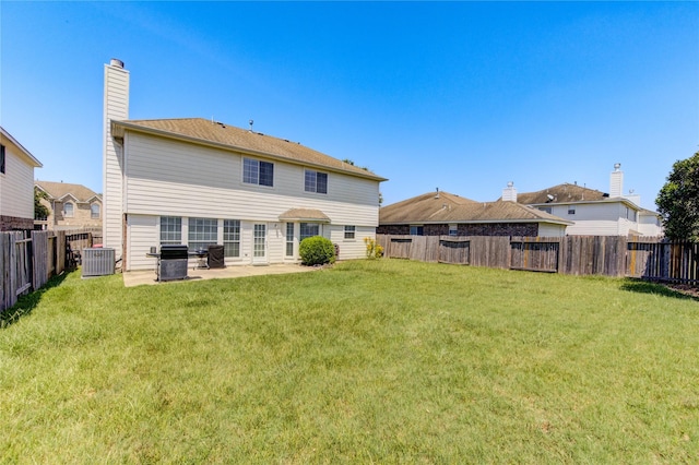 rear view of house with a lawn, a patio, a fenced backyard, a chimney, and cooling unit