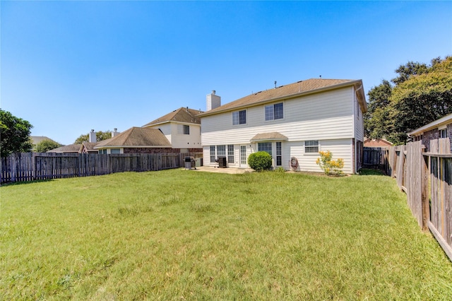 rear view of house with a fenced backyard, a chimney, and a yard