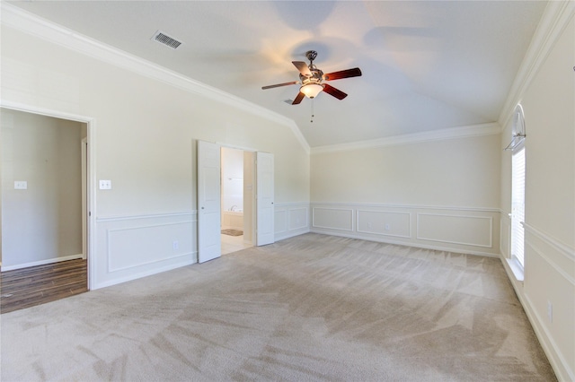 carpeted spare room with vaulted ceiling, crown molding, and a decorative wall