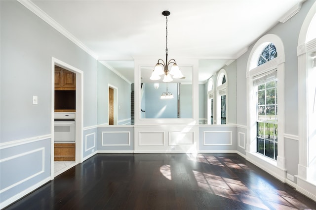 unfurnished dining area with a wainscoted wall, wood finished floors, an inviting chandelier, crown molding, and a decorative wall