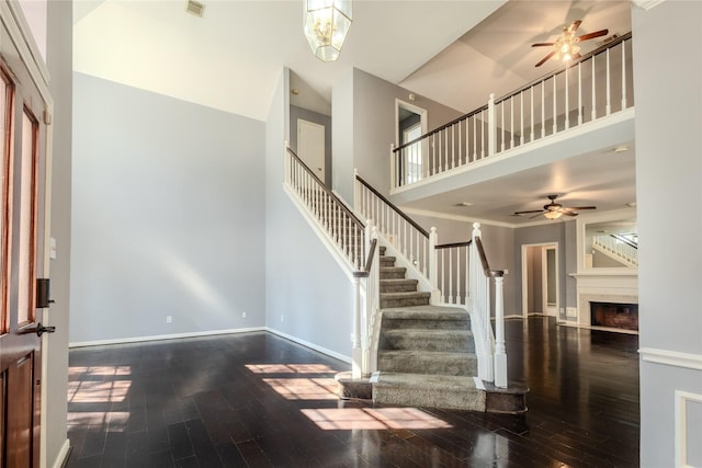 entryway with a high ceiling, a fireplace, wood finished floors, baseboards, and stairs