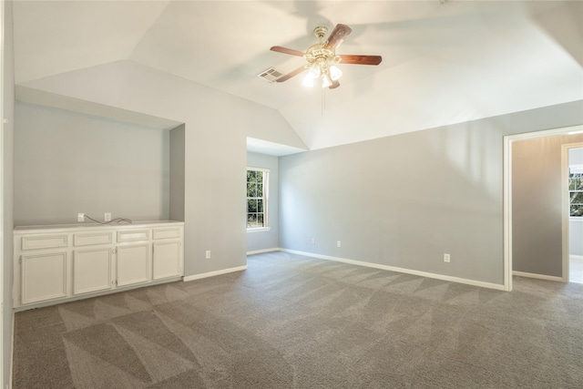 empty room featuring baseboards, visible vents, lofted ceiling, ceiling fan, and carpet flooring