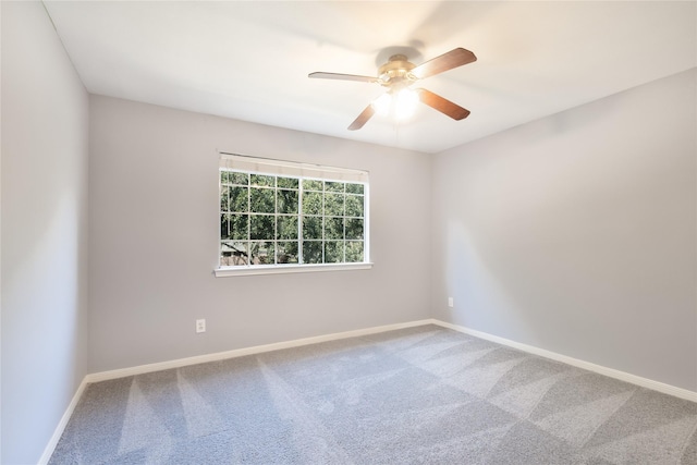 carpeted empty room with a ceiling fan and baseboards